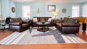 A living room with a sofa set, a coffee table, and decorative wall art. - Huge 4 Bedroom, Beach Block Condo with Pool and 3 Parking Spaces.   (North Wildwood)