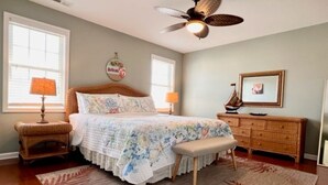 A bedroom with a bed, a wooden dresser, a bench, a ceiling fan, and a window with blinds. - Huge 4 Bedroom, Beach Block Condo with Pool and 3 Parking Spaces.   (North Wildwood)