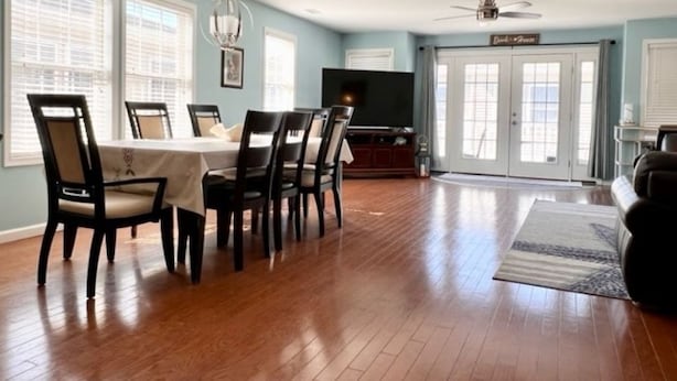 A spacious living room with hardwood flooring, a dining area with a table and chairs, a television, and a ceiling fan. - Huge 4 Bedroom, Beach Block Condo with Pool and 3 Parking Spaces.   (North Wildwood)