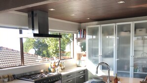 Eine moderne Küche mit dunklen Schränken, einer zentralen Kochinsel und einem großen Fenster.