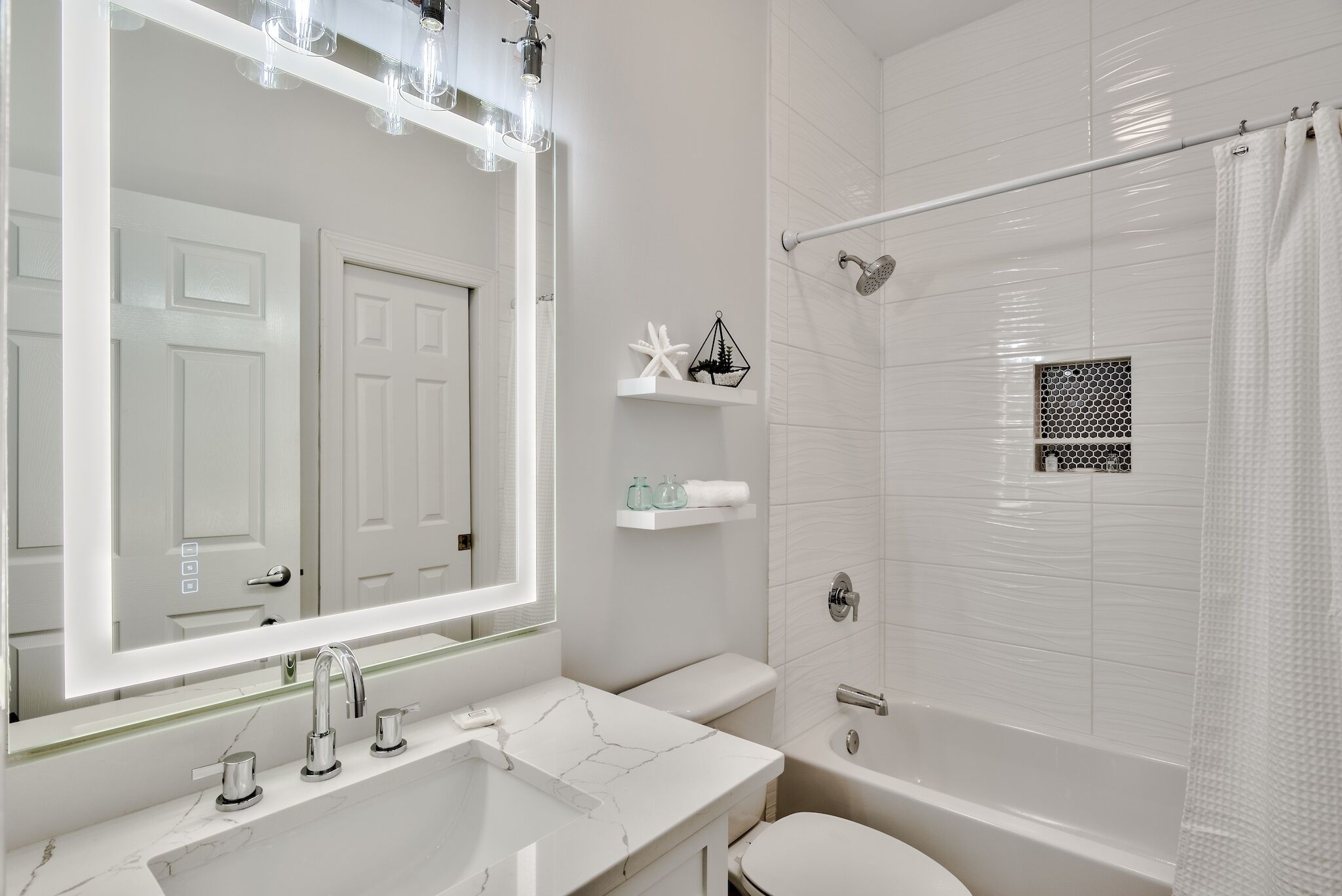 Une salle de bain moderne avec un grand miroir, un lavabo en marbre, des toilettes et un espace douche.