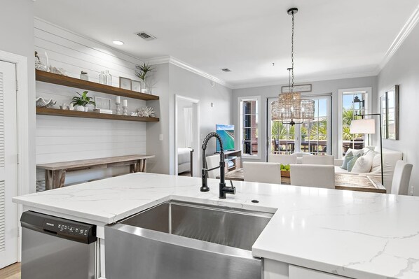 A modern kitchen with a built-in dishwasher, a stainless steel sink, and a dining area with a view.