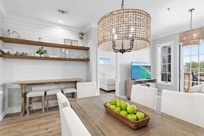 A modern kitchen with white cabinetry, wooden countertops, and a dining area with a wooden table and white chairs.