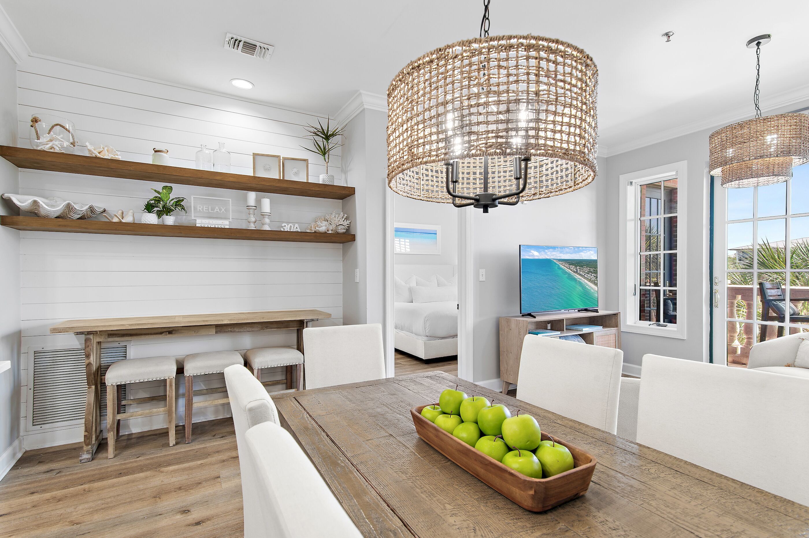 A modern kitchen with white cabinetry, wooden countertops, and a dining area with a wooden table and chairs.