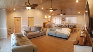 Ein geräumiges Wohnzimmer mit Holzboden, zwei Sofas, einem Couchtisch und einem Fernseher.
