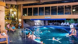 Una piscina interior con un cartel de 'NO DIVING', sillas de descanso y una escalera que conduce a un nivel superior.