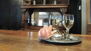 A table with a metal tray holding two wine glasses and a pink rose. - Bed & Breakfast in a 1795 Log Cabin on working farm, George Washington, Sr Suite (Swoope)
