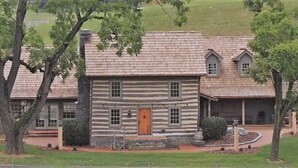 A log cabin with a central wooden door, multiple windows, and a sloped roof. - Bed & Breakfast in a 1795 Log Cabin on working farm, George Washington, Sr Suite (Swoope)