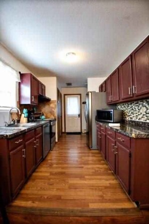 Fully equipped kitchen with microwave, refrigerator, and sink, plus a window for natural light.