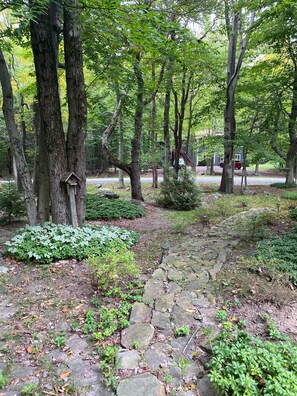 Stroll through the serene park, surrounded by lush greenery and mature trees along a winding stone pathway.