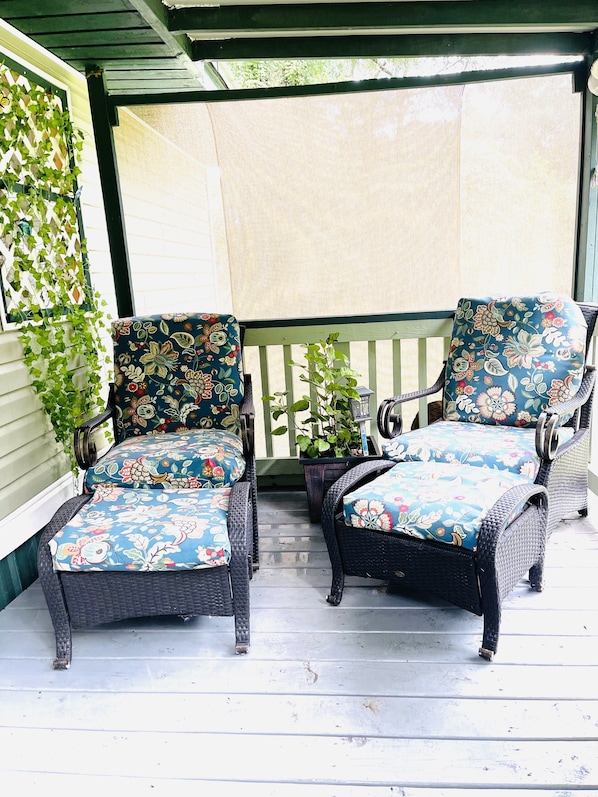 A covered porch with two wicker chairs and a small table, surrounded by potted plants and a wooden railing. - Springs Cottage 3/1 sleeps 8, near Ginnie, Fanning Springs , Manatee and blue (Fanning Springs)