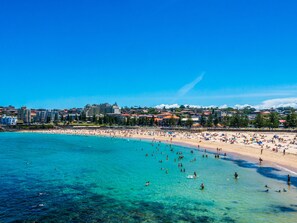 A beach with clear turquoise water, a sandy shore, and buildings in the background. - The Arden 7 Coogee. New Large Quiet Ocean View Balcony Apartment, Next to Beach (Coogee)