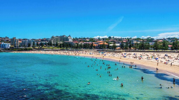 A beach with clear turquoise water, a sandy shore, and buildings in the background. - The Arden 7 Coogee New Beachside Ocean View Apt (Coogee)