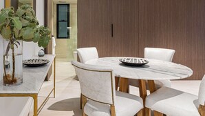 A modern dining area with a marble table, white upholstered chairs, and a potted plant. - The Arden 7 Coogee New Beachside Ocean View Apt (Coogee)