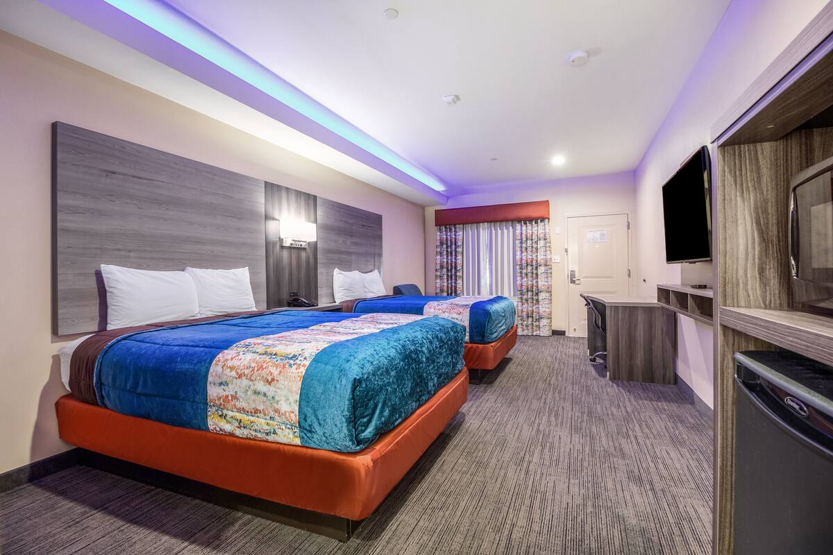 Habitación de hotel con dos camas, televisión, escritorio y minibar.