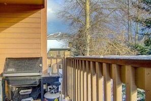 A barbecue grill with a water container and a propane tank, a wooden deck, and a view of a mountain. - Weekly Deals! Remodeled Retreat + Hot Tub + Garage (Steamboat Springs)