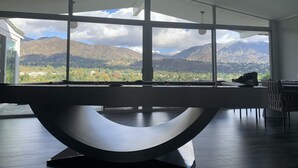 A modern room with a pool table, large windows offering mountain views, and a minimalist design.