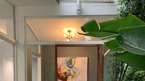 A modern entrance with a stone pathway, a wooden door, and a large abstract painting on the wall.