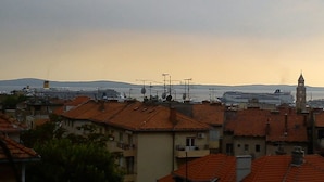 A coastal cityscape with residential buildings and a large cruise ship docked at the port. - Apartments Bulic (Split)