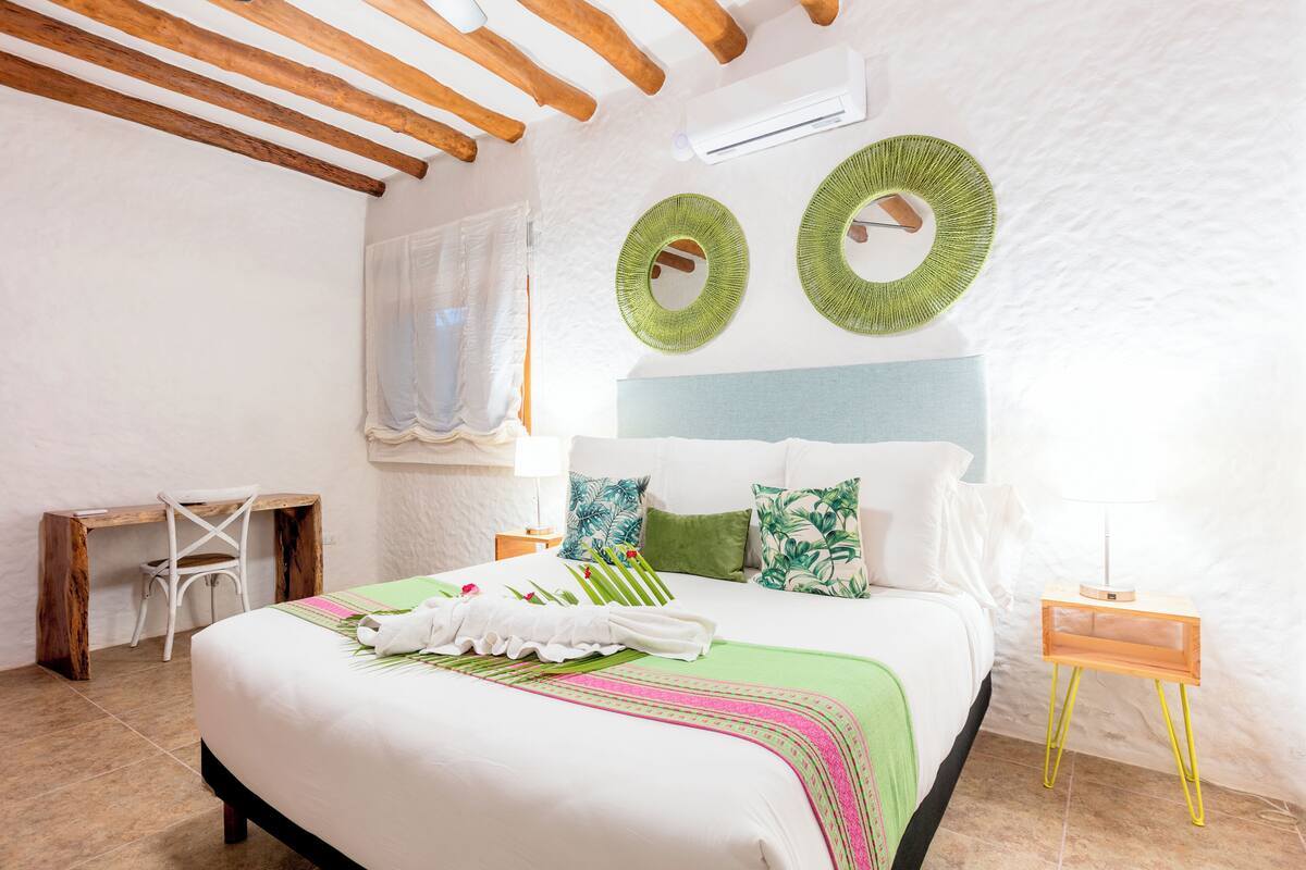 A bedroom with a bed, a desk, and a nightstand.