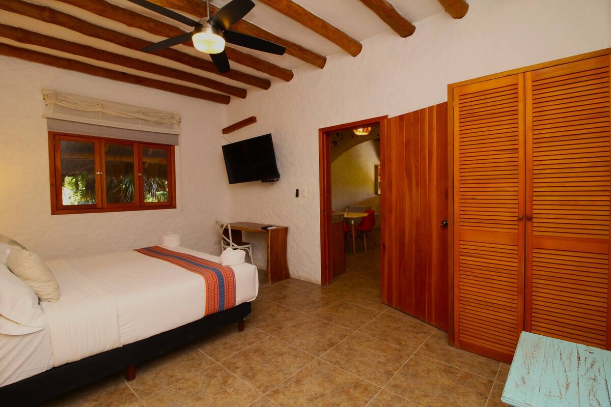 A bedroom with a bed, a desk, a TV, and a wardrobe.