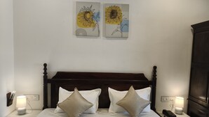 Una cama bien hecha con dos almohadas, un cabecero de madera y dos mesitas de noche con lámparas y un teléfono.