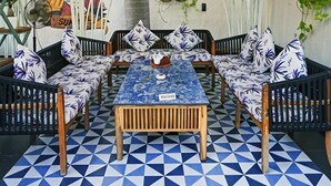 Un rincón al aire libre acogedor, con techo estampado, una mesa central y una variedad de sillas y sofás.