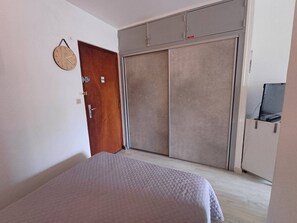 Quarto com cama, guarda-roupa e porta.