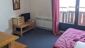 A room with a bed, a desk, a television, and a radiator.