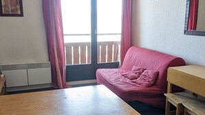 A room with a wooden table, a red sofa, and a wooden bench.