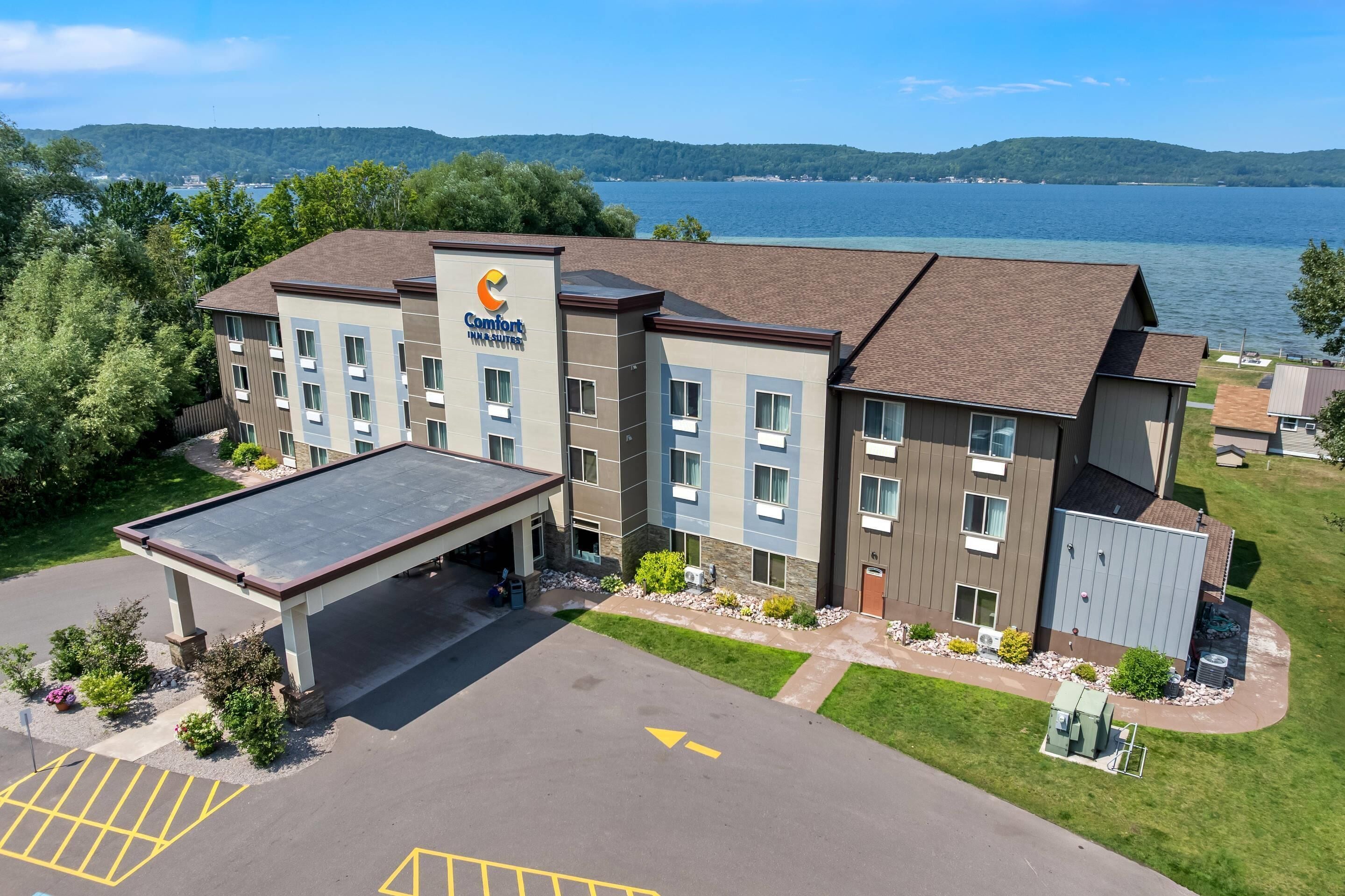 Een Comfort Inn hotel met een parkeerplaats, een overdekte ingang en uitzicht op een meer.