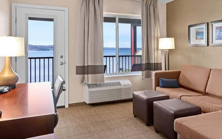 A hotel room with a view of the sea, a sofa, a desk with a lamp, and a heater.