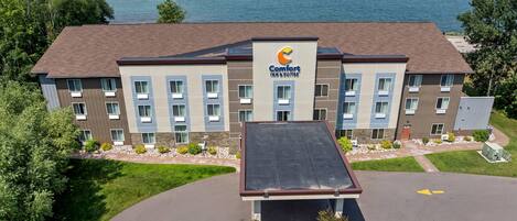 A multi-story hotel with a flat roof and a sign reading "Comfort Inn Suites."