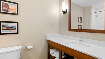 A bathroom with a white sink, a mirror, and two framed pictures on the wall.