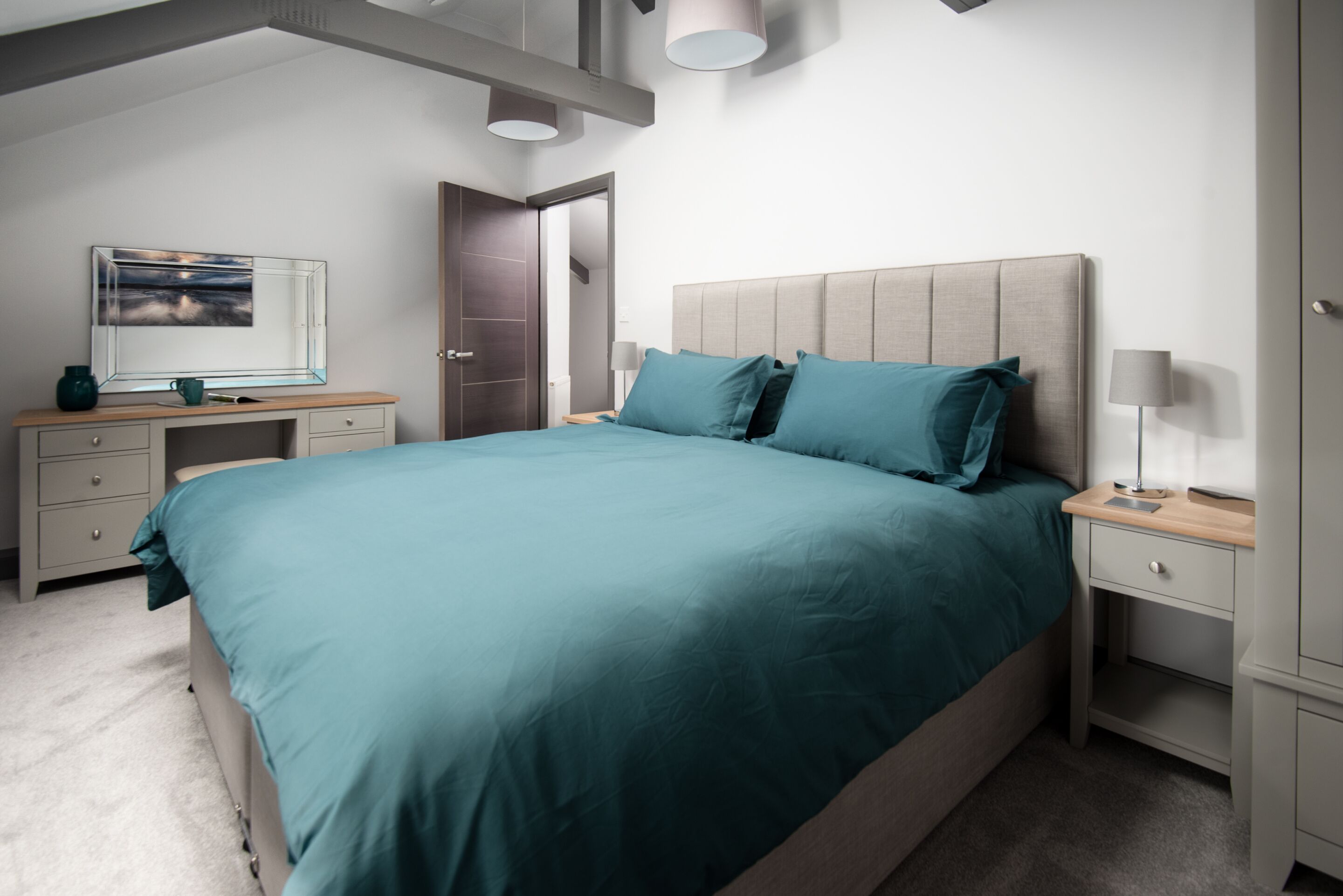 Quarto moderno com cama grande, escrivaninha e cadeira.