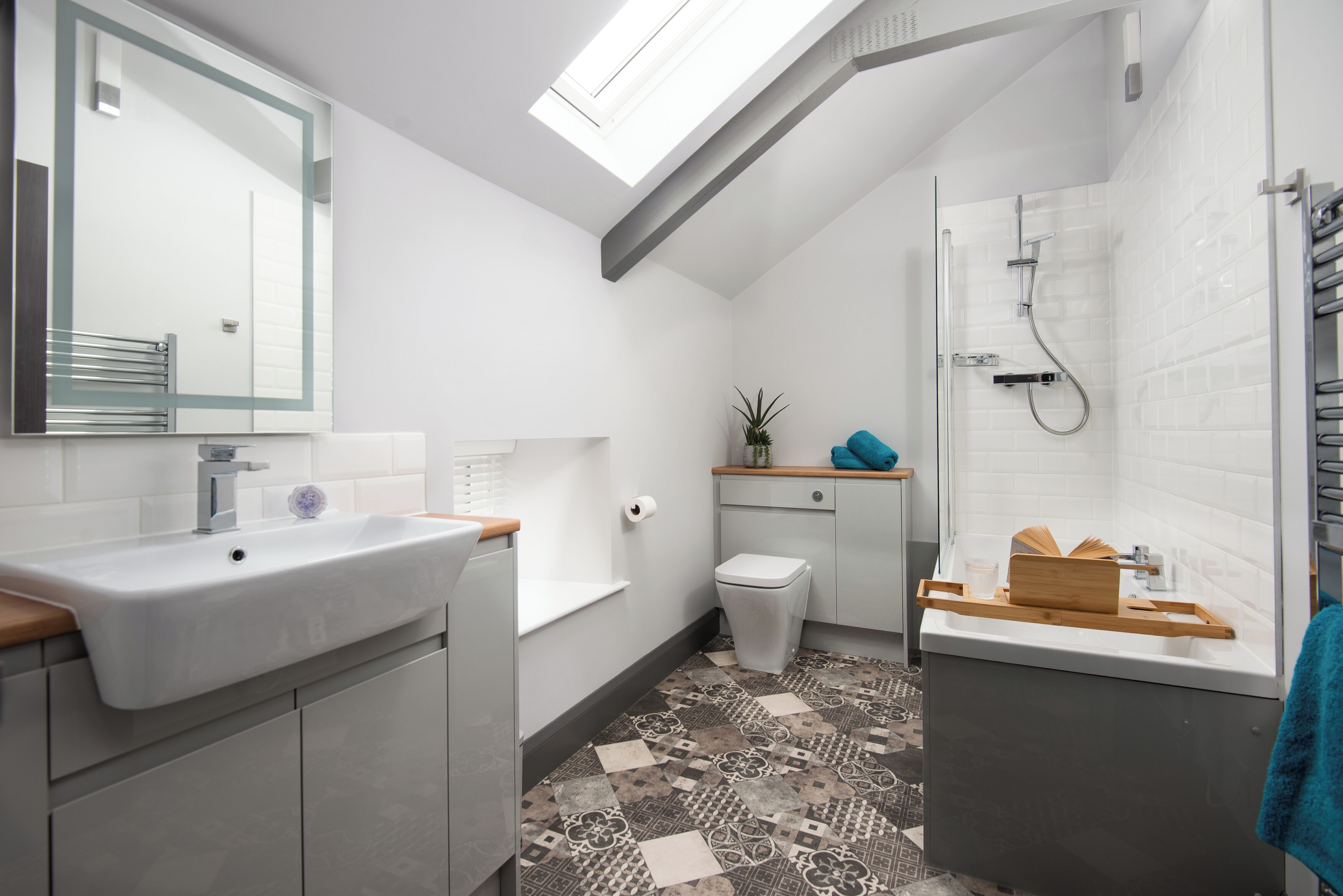 A modern bathroom with a skylight, a shower, and a sink.