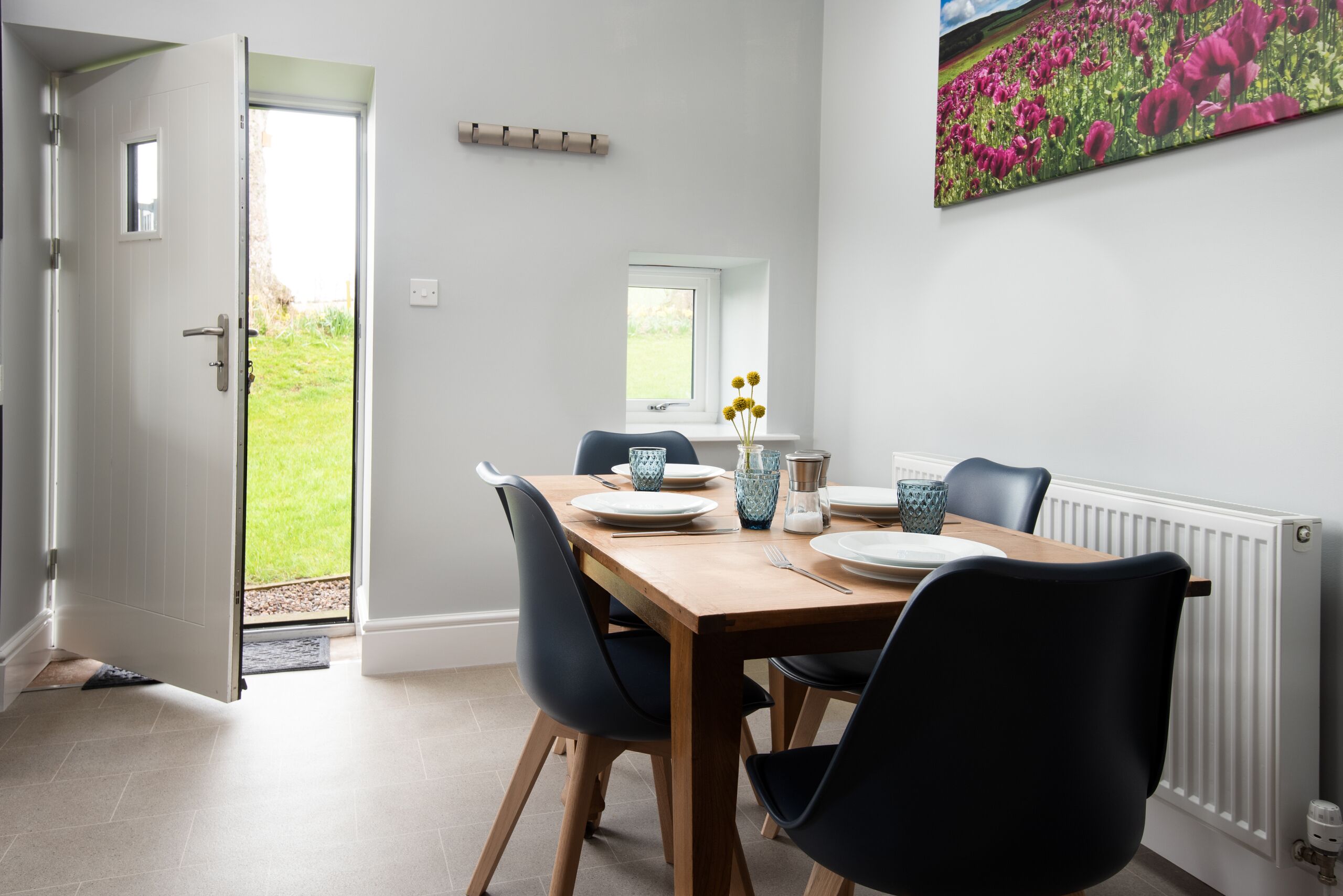 A dining area with a wooden table, black chairs, and a window with a view of a garden.