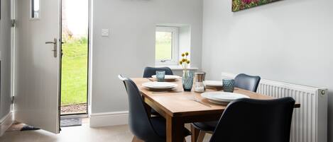 A dining area with a wooden table, black chairs, and a window with a view of a garden.