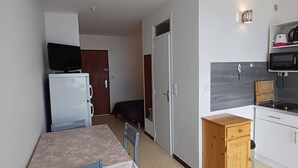 A compact kitchen with a dining area, a refrigerator, a microwave, and a small cabinet.