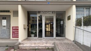 A building entrance with a sign reading 'SEVIGNE 1' and a parking sign indicating a station for self-service car parking.