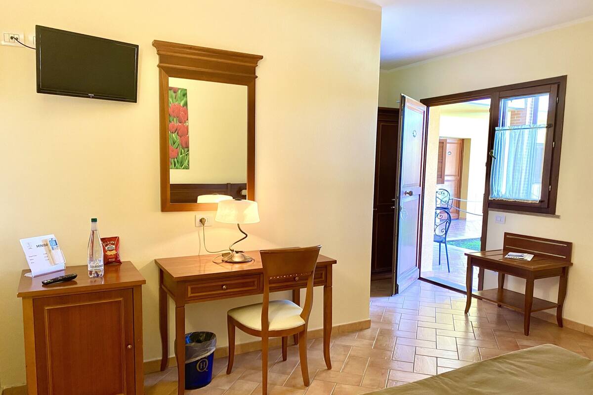 Une chambre d’hôtel équipée d’un bureau, d’une chaise, d’un lit, d’une télévision et offrant une vue sur l’extérieur.
