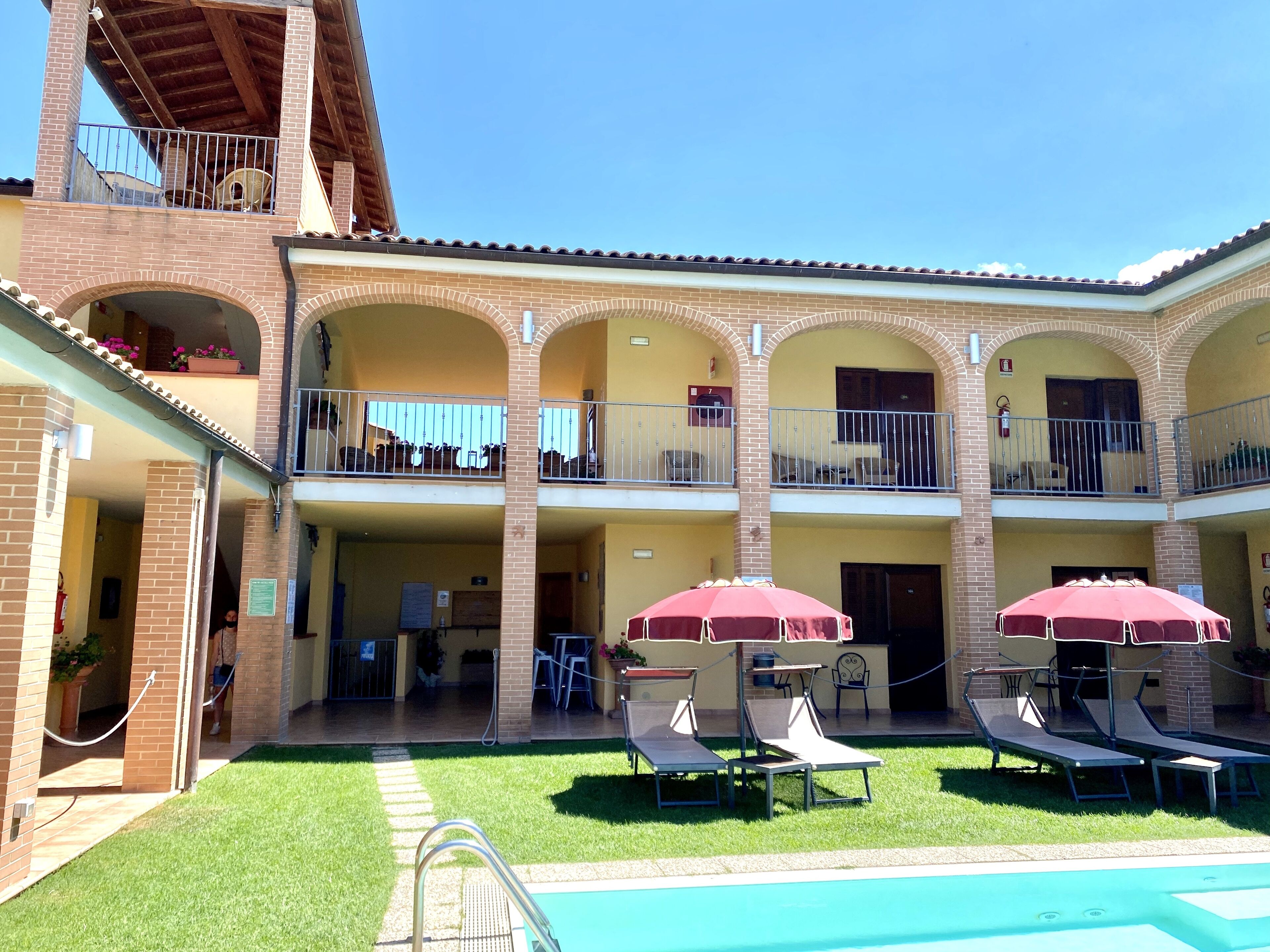 A hotel with a courtyard, outdoor seating, and a swimming pool.
