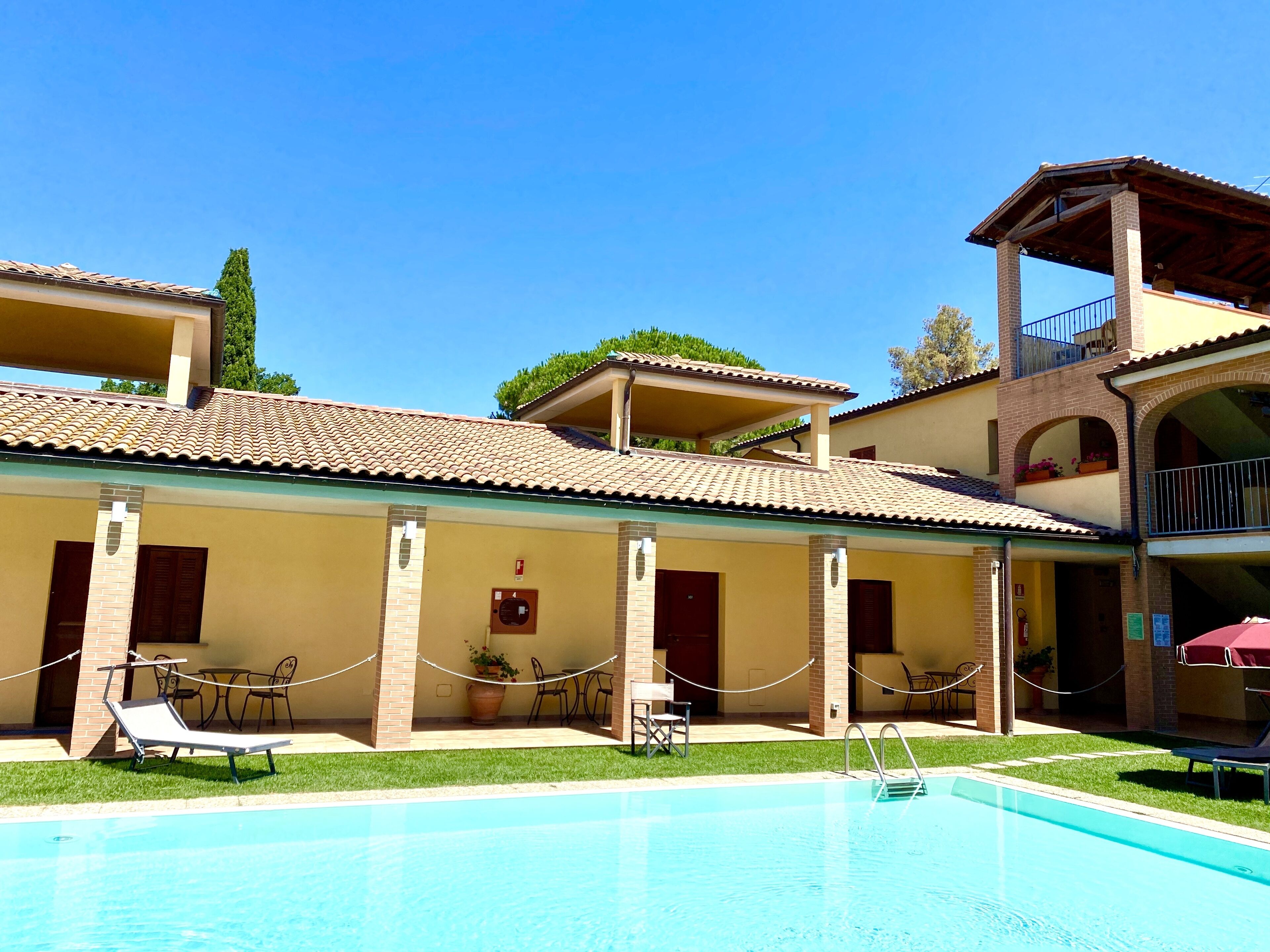 A poolside area with a swimming pool, lounge chairs, and a covered seating area.