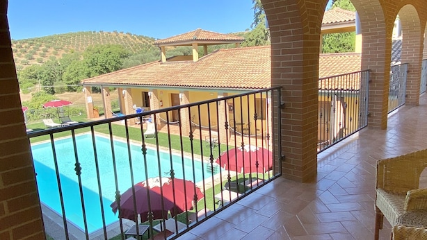 Ein überdachter Außenbereich mit Pool, Ziegelbögen und Gartenmöbeln.