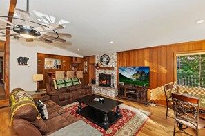 Een woonkamer met een open haard, een televisie en een eethoek.