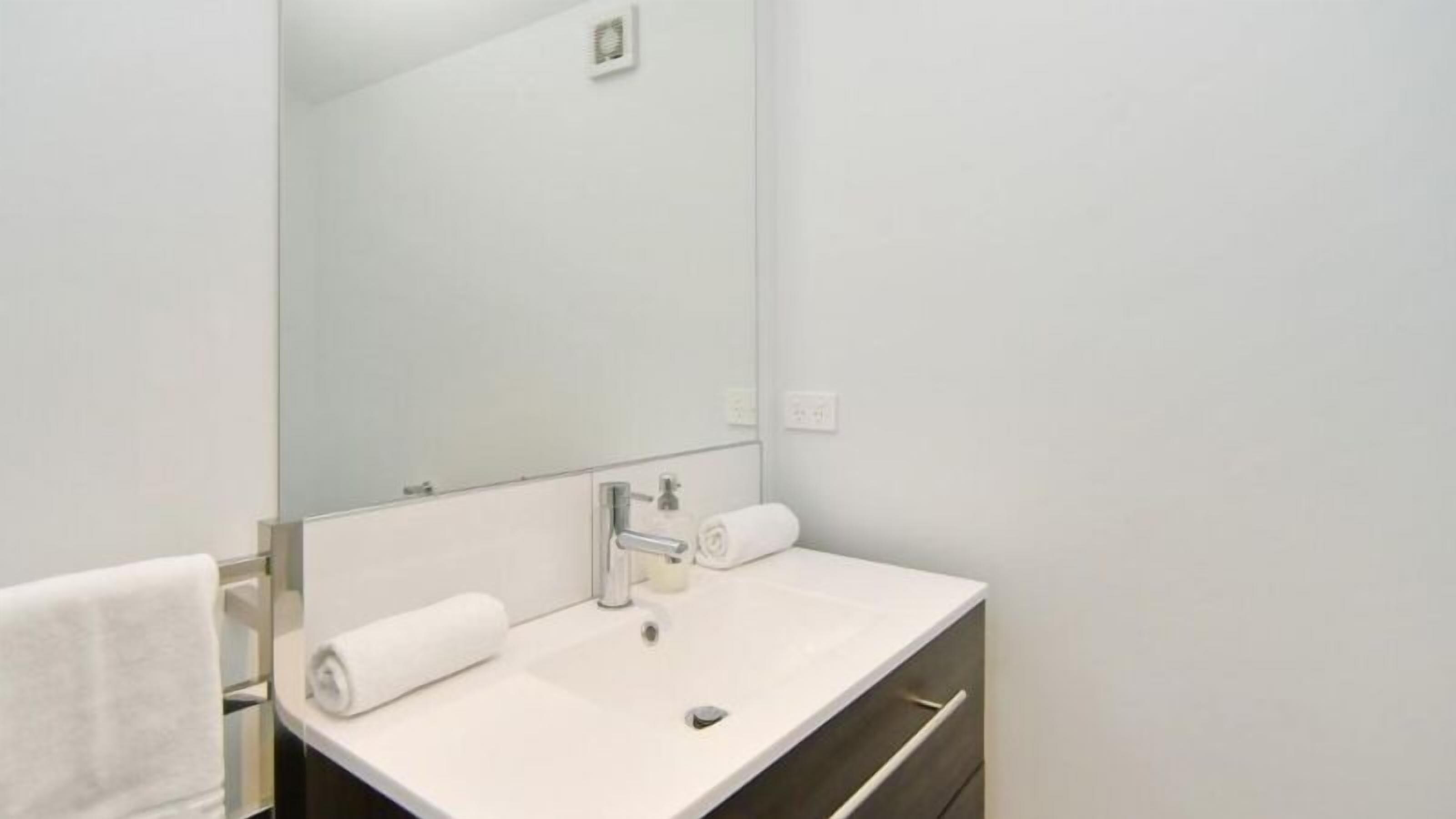 Een moderne badkamer met een wit wastafelmeubel, een spiegel en een handdoek.
