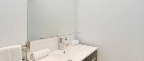 Een moderne badkamer met een wit wastafelmeubel, een spiegel en een handdoek.