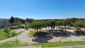 A park with trees, a circular area, and a building in the background.