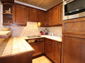 A kitchen with wooden cabinets, a stainless steel oven, and a tiled backsplash.