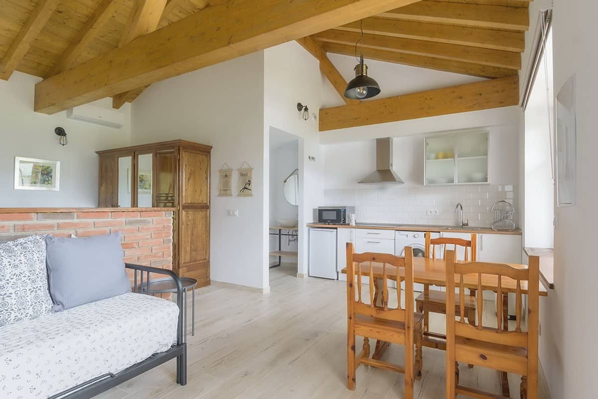 A modern kitchen with white cabinets, a wooden dining table, and a built-in microwave.